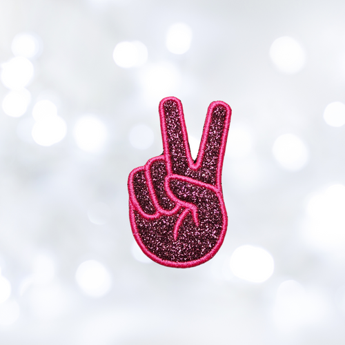 Pink glittery peace sign patch on a white background